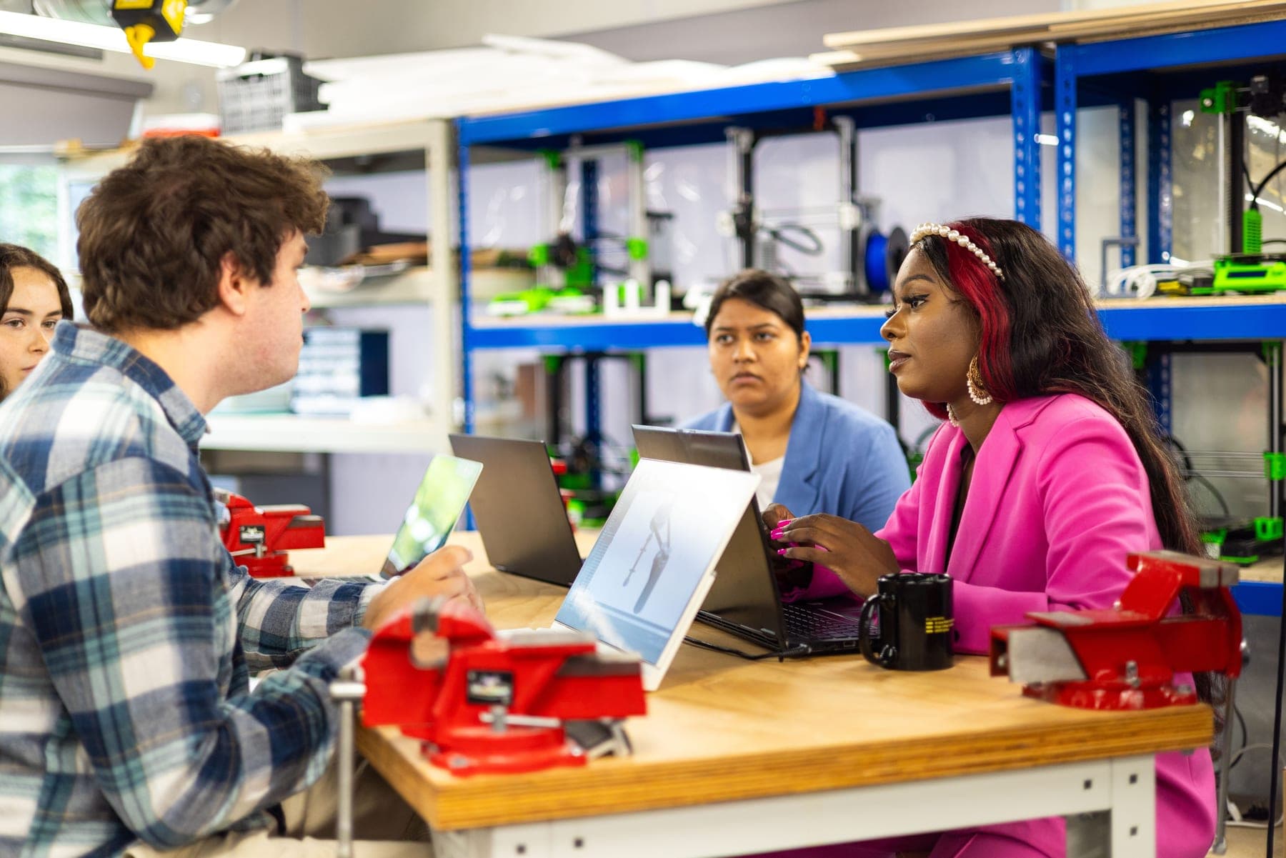 A technical workshop discussion with laptops and prototyping equipment
